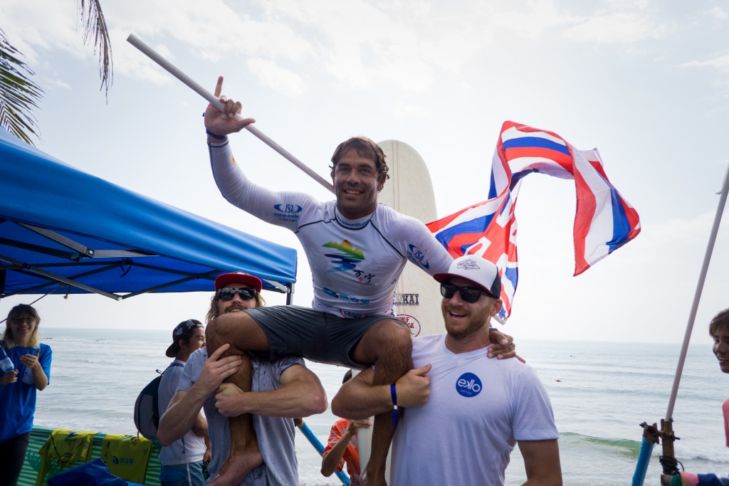 Kai Sallas is chaired up by beach my fellow competitors Ben Skinner (ENG) and Phil Rajzman (BRA), representative of the camaraderie between teams at the ISA World Longboard Surfing Championship. Photo: ISA / Sean Evans
