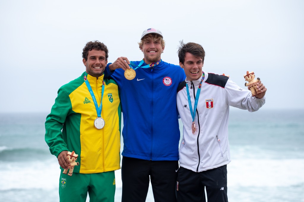 De izquierda a derecha: Vinnicius Martins de Brasil, Connor Baxter de Estados Unidos, e Itzel Delgado de Perú muestran sus medallas en el podio de las Carreras SUP Masculinas en los Juegos Panamericanos Lima 2019. Foto: ISA / Pablo Jimenez 